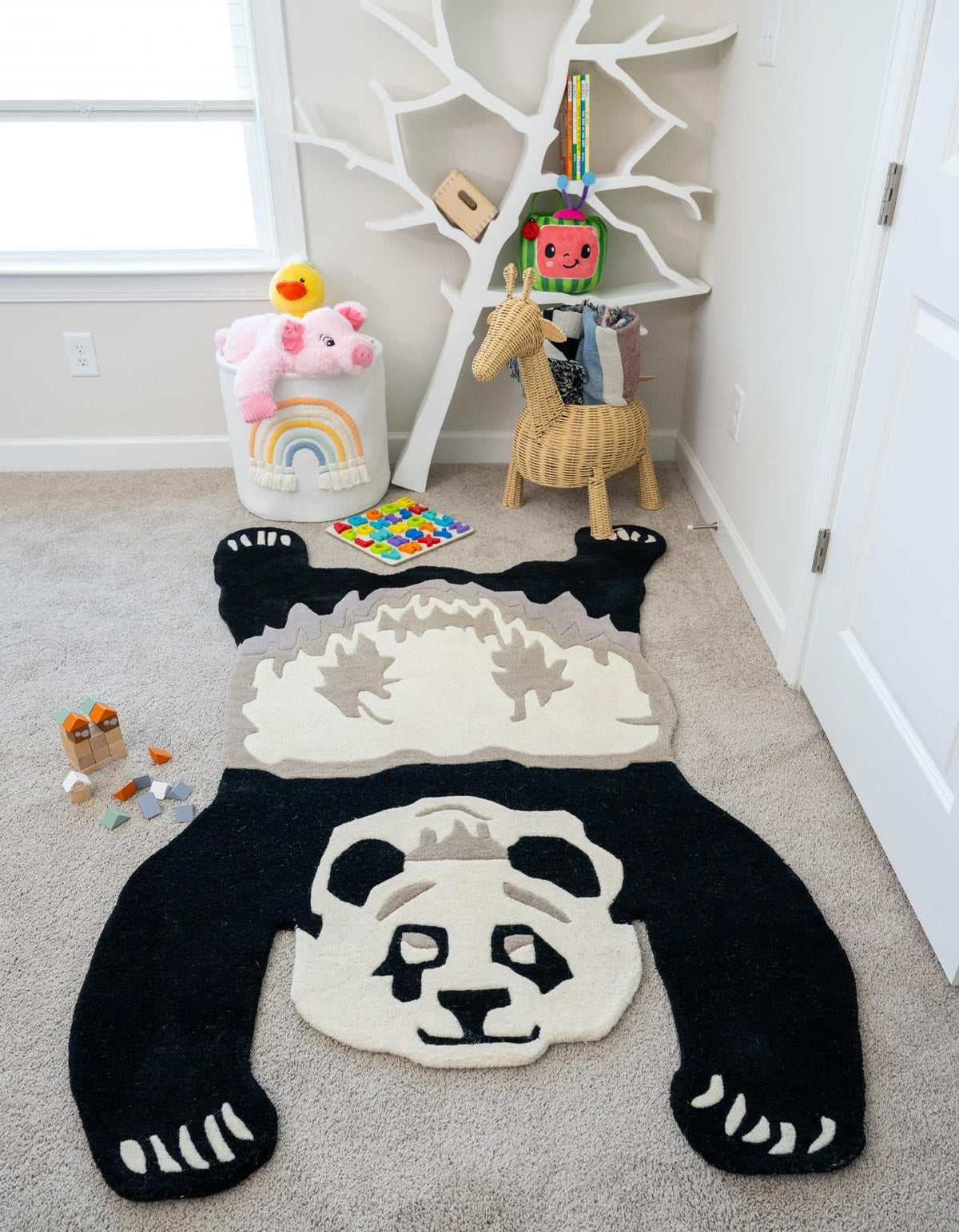 Kids rug featuring a playful black and white panda design in a bright children's playroom with toys and storage.